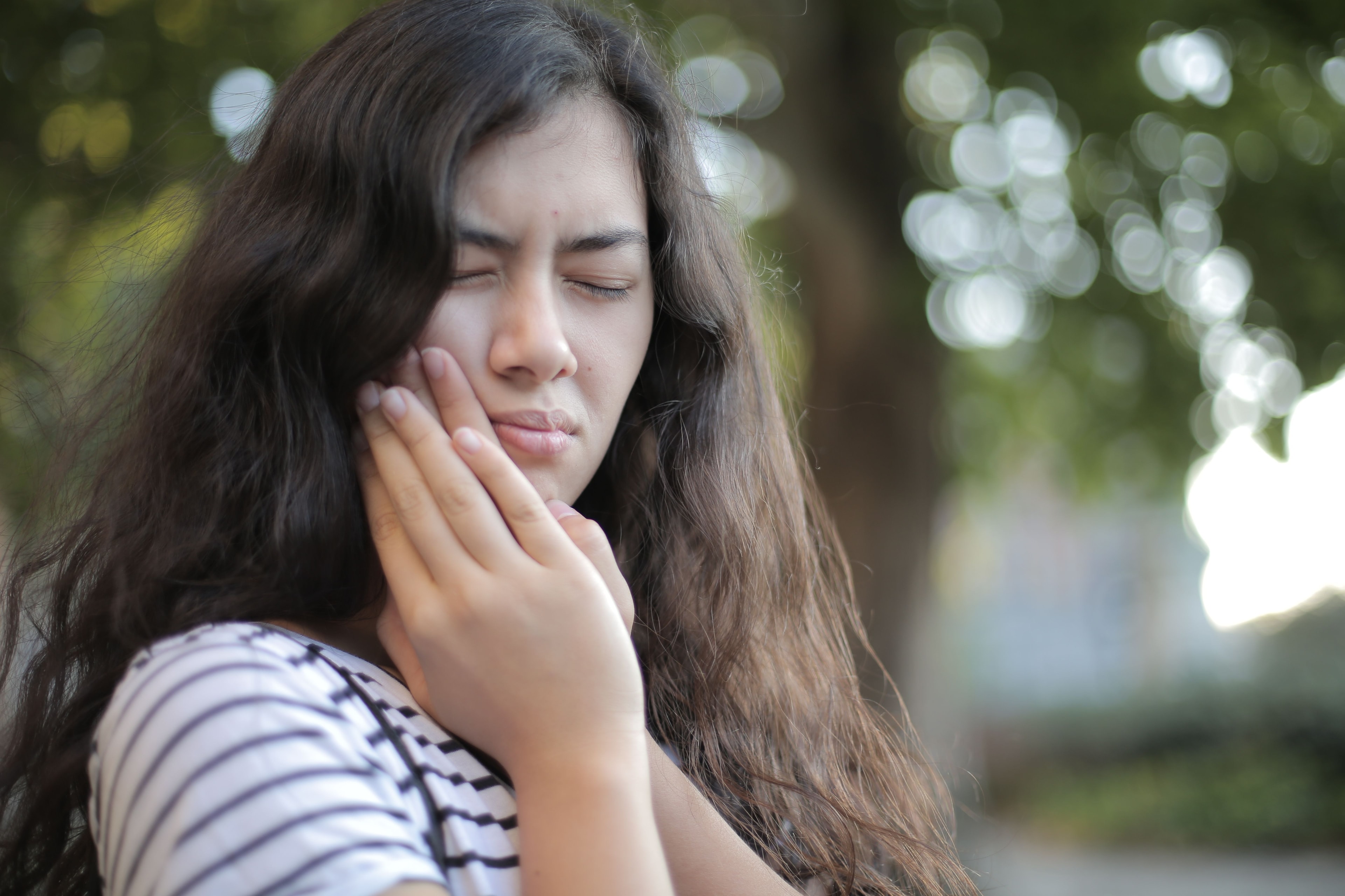 Woman holding jaw in TMJ pain discomfort